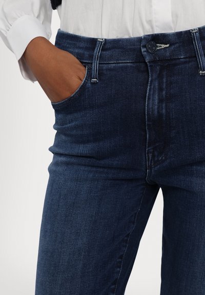 Dunkelblaue Denim-Jeans mit einem figurbetonten Design, Fronttaschen und einem Knopfverschluss. Der Stoff weist eine weiche Textur mit leichter Ausbleichung auf.