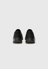 Black slip-on shoes feature a textured upper with a diamond pattern and soft, cushioned soles. Dual nature of materials enhances comfort and flexibility.