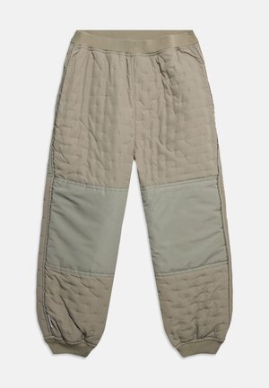 Μπεζ παντελόνι με ραφές, με ελαστική μέση και μανσέτες, με λείες επιδιορθώσεις στα γόνατα και πλαϊνές τσέπες, απλωμένο επίπεδα σε λευκό φόντο.