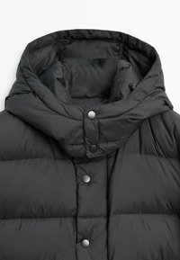 Schwarze Daunenjacke mit hohem Kragen und Druckknopfverschluss. Die Außenseite ist glatt, mit gestepptem Muster und einer Kapuze.