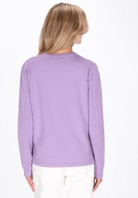 Lila top met lange mouwen en een gestructureerd patroon op de mouwen. Gemaakt van gebreid materiaal, met een ronde halslijn en een losse pasvorm.
