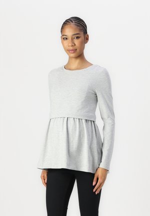 Top lung cu mânecă lungă, de culoare gri deschis, cu un corset ajustat și o margine evazată, realizat dintr-un material moale. Are un guler rotund și un design plisat.