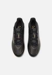 Black athletic shoes featuring a sleek design with vertical stripes, round toe, lace-up front, and subtle gold accents.