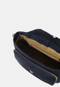 Borsa in nylon blu navy con dettagli in oro, dotata di una tasca esterna con zip e un ampio interno rivestito in tessuto beige.