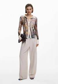 Košulja s dugim rukavima i kopčanjem na gumbe, s cvjetnim i apstraktnim uzorkom, kremasti ovratnik i manšete. Uparen sa širokim bež hlačama svijetle nijanse.