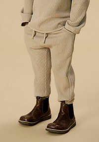 Beige teksturert strikket topp og matchende ribbestrikkede bukser, kombinert med brune skinn Chelsea-støvler med elastiske sidepaneler og robust såle.