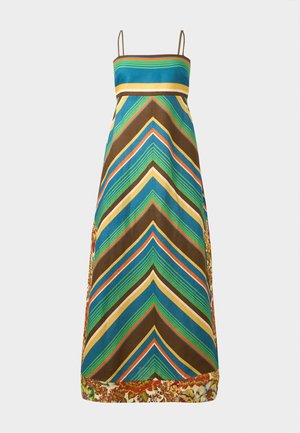 Kobieta w bezrękawnikowej, paskowanej, maxi sukience z kwiatowymi akcentami, trzymająca szydełkowaną torbę typu tote i nosząca czarne, otwarte szpilki.