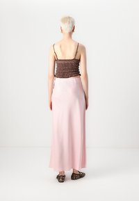 Rjav smockiran top s tankimi naramnicami, ki je v kombinaciji z dolgim satenskim roza krilom. Obleka se ponaša z elegantno silhueto in diskretno sijočim izgledom.