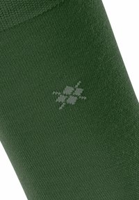 Calzino verde con un design a maglia strutturata. Presenta un logo floreale grigio chiaro sul lato. Il materiale sembra morbido ed elastico.