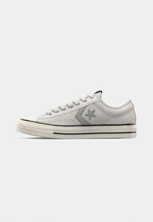 Baskets basses grises en suede perforé, avec un logo étoile noir, un capuchon en caoutchouc blanc et une semelle contrastante noir et blanc.