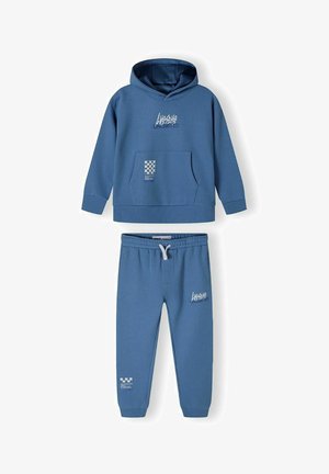 Kapuccinos pulóver és jogger szett puha kék anyagból. Elöl zseb, logónyomtatás és elasztikus derékpánt húzózsinórral.
