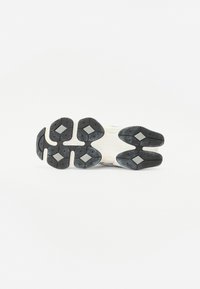 Sole of a white and black athletic shoe with textured tread and diamond-shaped rubber grips on a plain white background.
