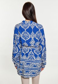 Camicia blu a fantasia con design floreali e geometrici, maniche lunghe e vestibilità rilassata, realizzata in un tessuto leggero.