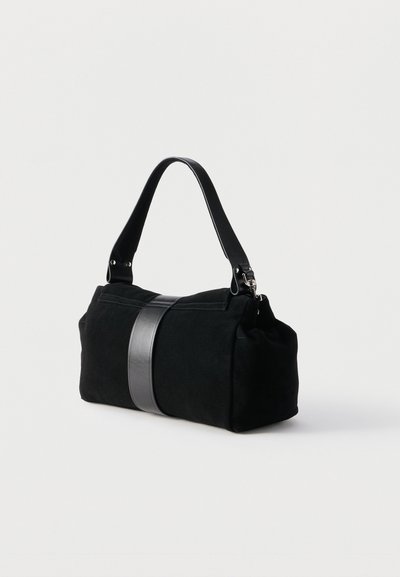 Μαύρη ορθογώνια τσάντα με φαρδιά δερμάτινη λουρά και χερούλι ώμου, ακουμπισμένη σε απλό ανοιχτόχρωμο φόντο.