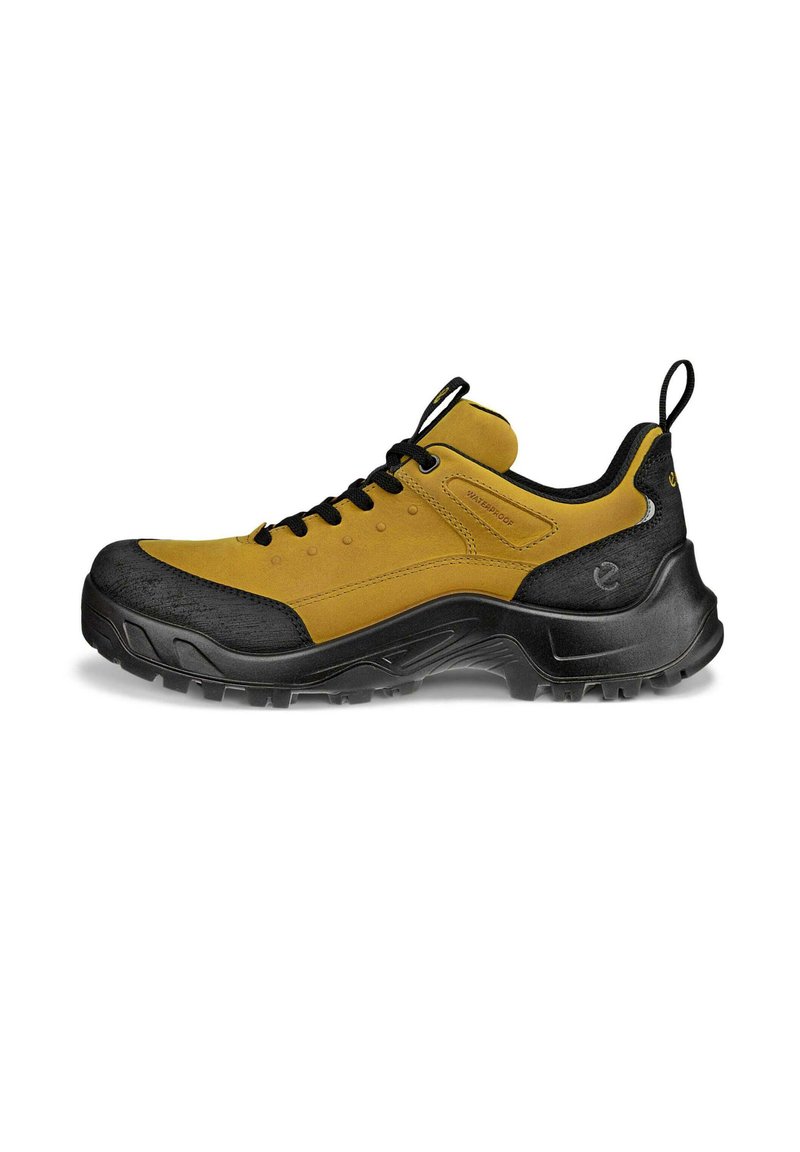 Scarpa da trekking impermeabile con tomaia in suede giallo e punta in gomma nera. Presenta un robusto design con lacci e un pratico cinturino per il tiraggio.