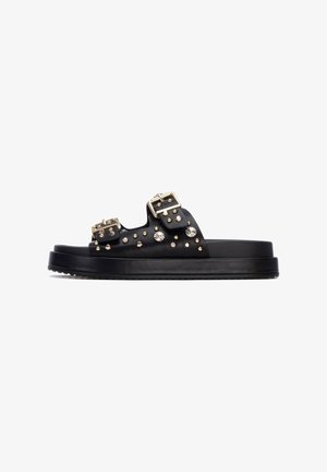 Sandalias de plataforma negras con dos hebillas y tachuelas decorativas. Material liso con acabado mate y suela texturizada para mayor agarre.