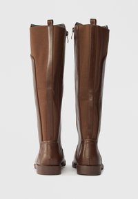 Botas altas de couro e tecido castanho com um acabamento suave, fechos laterais em zíper e uma sola resistente. Painéis texturizados realçam o design.