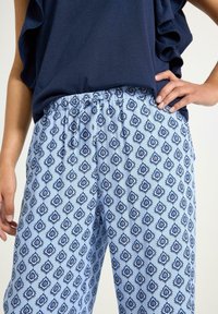 Pantaloni blu a fantasia con un design a diamante bianco e blu navy, dotati di una cintura elastica e una vestibilità comoda. Tessuto dalla texture liscia.