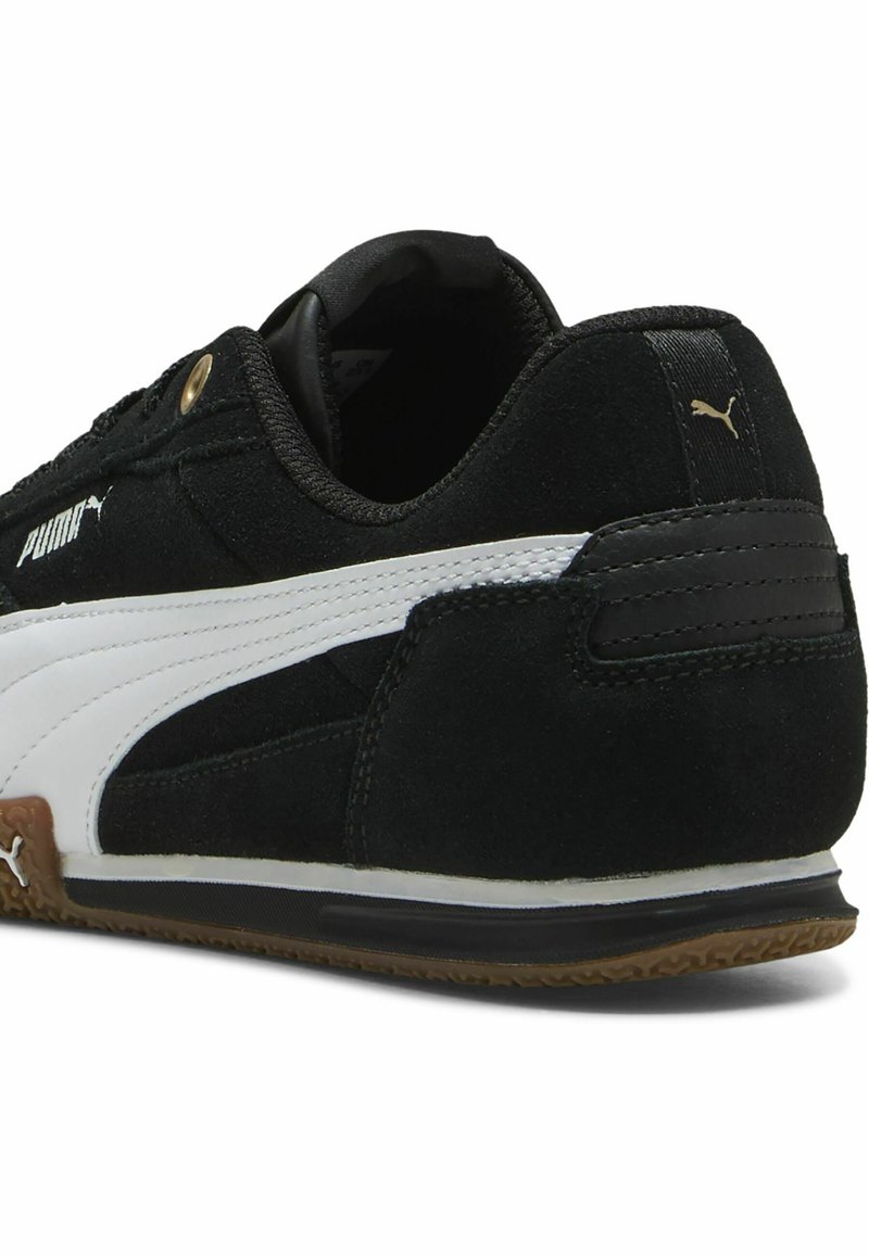 Zwarte suède sneaker met witte leren accenten, gumrubberen zool en subtiele branding. Heeft een gestikte kraag en een slank ontwerp.