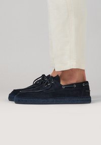 Espadrilles de ante azul marino con cordones decorativos, suelas de goma y detalles cosidos. Presenta ojales de metal y un borde de yute trenzado.