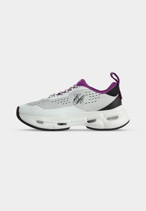 Chaussure de sport blanche avec accents violets, logo noir sur le côté, tige en mesh perforé, semelle épaisse et rembourrée, et languette au talon.