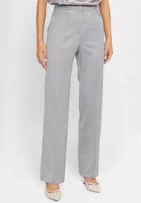 Szare dopasowane spodnie z prostą nogawką, o gładkiej fakturze i subtelnych detalach kieszeni bocznych. Noszone z beżowymi butami.