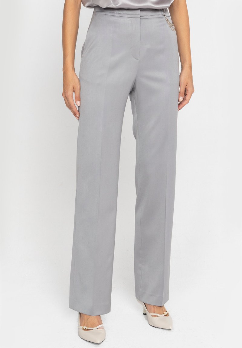 Szare dopasowane spodnie z prostą nogawką, o gładkiej fakturze i subtelnych detalach kieszeni bocznych. Noszone z beżowymi butami.