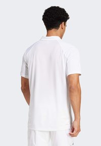 White short-sleeve polo shirt with a breathable, textured fabric, featuring a classic collar and contrasting raglan sleeves.