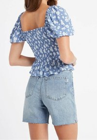 Haut à manches bouffantes fleuri bleu avec un dos froncé et un ourlet peplum, associé à un short en denim taille haute bleu clair.