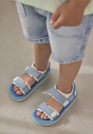 Sandalias de doble tira en azul claro con detalles en tonos pastel, con parte superior texturizada y suela resistente, con cierres ajustables de velcro.