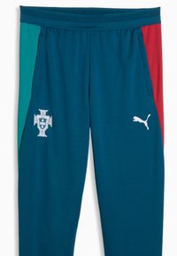 Pantalon de sport bleu sarcelle foncé avec des panneaux latéraux rouges et verts, écusson de football du Portugal sur la cuisse gauche, et logo Puma blanc sur la cuisse droite.