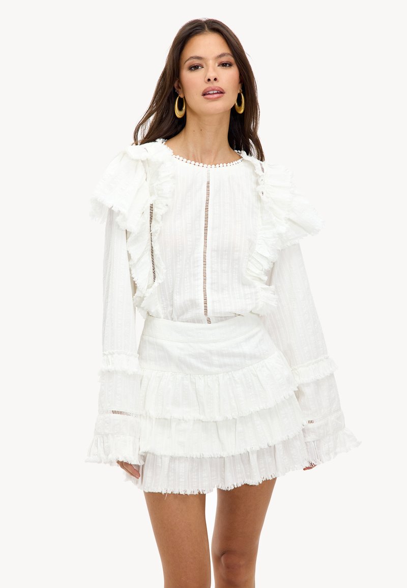 Witte jurk met gelaagde ruffles, textuurstof, lange mouwen en een knoopsluiting aan de voorkant. Bevat decoratieve afwerking langs de halslijn.