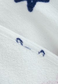 White towel with a soft, textured surface featuring blue star patterns. Edges are stitched with white thread for durability.