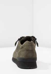Sneaker verde in suede con pannelli laterali in rete, tallone imbottito e suola in gomma nera. Presenta una chiusura con zip e un branding discreto sul tallone.