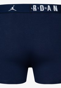 Marineblaue Herrenboxershorts aus elastischem Stoff, mit einem weichen Bund, auf dem "JORDAN" in weißen Buchstaben steht. Glatte Oberfläche.