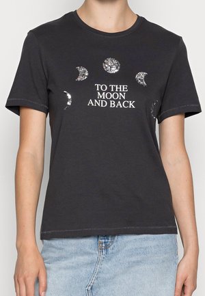 Sort kortærmet t-shirt med sølvfarvede månefaser over hvid tekst, der lyder "TO THE MOON AND BACK," båret med lyseblå denimjeans.