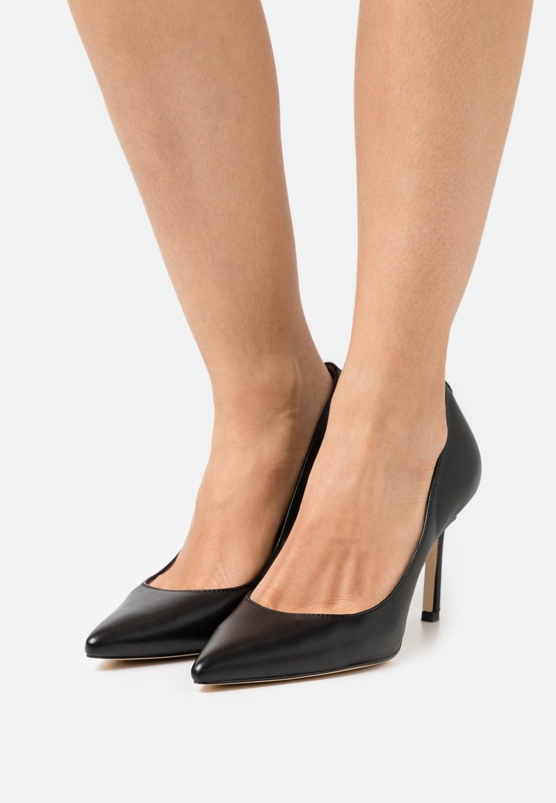 Escarpins noirs en cuir avec un bout pointu et un talon stiletto slim. Présentent un design à décolleté bas à l'avant et une texture lisse.