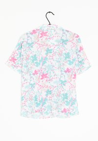 Camisa de manga corta con un patrón floral en rosa y verde azulado sobre un fondo blanco, confeccionada en una tela ligera. Cuélga de un gancho negro.