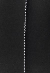 Czarna tkanina o gładkiej fakturze z wyraźnym, białym i czarnym plecionym suwakiem biegnącym pionowo.