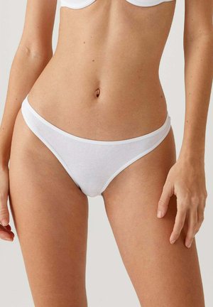 White cotton thong underwear with a soft ribbed texture, low-rise design, and minimal coverage. Features a thin elastic waistband.