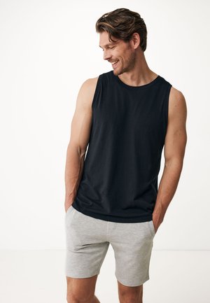 Zwarte mouwloze shirt van katoen, gecombineerd met lichtgrijze shorts. De stof lijkt zacht, met een ontspannen pasvorm en zonder patronen.