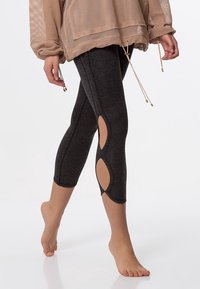 Leggings de sport noirs avec des découpes sur les mollets, fabriqués à partir d'un matériau extensible, conçus pour le confort et la liberté de mouvement.