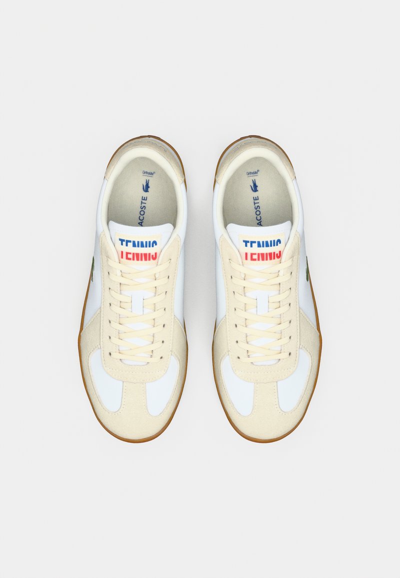 White and beige tennis shoes with a gum sole, featuring a lace-up design, soft textile upper, and "TENNIS" graphic on the tongue.