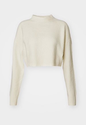 Pulover scurt, de culoare crem, realizat dintr-un material moale. Prezintă o gâtă înaltă, cu ranforsare, și mâneci lungi cu mansete ranforsate. Textură netedă, design minimalist.