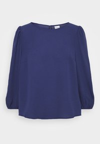 Blouse bleu marine avec un col rond, des manches longues bouffantes et une fermeture éclair au dos. Fabriquée en tissu lisse et léger.