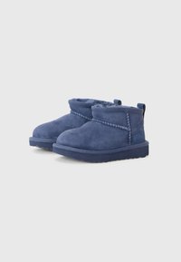Bottines en suede bleu avec un intérieur doux, bout rond et semelle texturée. Elles présentent une couture décorative sur le côté.