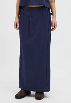 Navy blue, long skirt made of lightweight fabric, featuring a wrap design with side ties and a straight hem. Worn with brown ankle boots.