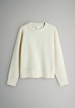 Krēmkrāsas džemperis no mīksta, teksturēta auduma. Tam ir apaļa kakla izgriezuma, garas piedurknes un ribotie aproces un apakšmala.