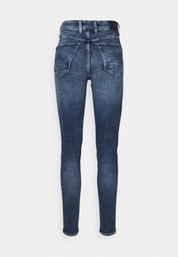 Jeans ajustados en denim azul oscuro con efecto desgastado, con una cintura alta, cinco bolsillos y detalles de costura en los bolsillos traseros.