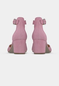 Ροζ σουέτ παπούτσια με τακούνι, κλειστή πλάτη, ρυθμιζόμενο κούμπωμα με πόρπη και τετράγωνο τακούνι, με απαλή υφή και απαλό χρώμα.